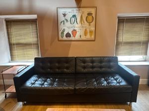 a black leather couch in a living room with windows at Urban Perch in Penrith