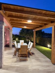 a patio with a table and chairs under a wooden pergola at Villa Aurelia - Pool, BBQ & Tennis Court - San Teodoro in San Teodoro