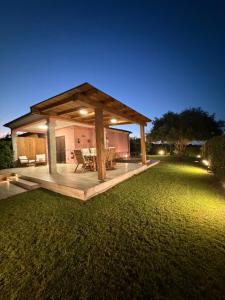 a pavilion with a picnic table on a lawn at night at Villa Aurelia - Pool, BBQ & Tennis Court - San Teodoro in San Teodoro