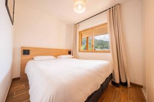 a bedroom with a large white bed and a window at Résidence Arya - Living Stone in Vars