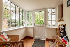 a living room with windows and a chair at Stable Cottage - Elie in Elie