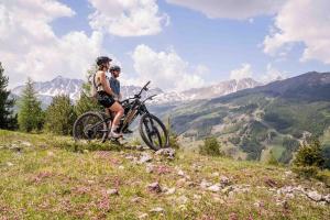 two people standing on a hill with a bike at Résidence Arya - Living Stone in Vars