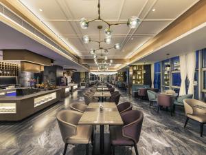 a restaurant with tables and chairs and a bar at Mercure Chengdu Downtown Hotel in Chengdu