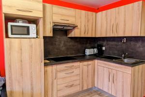 a kitchen with wooden cabinets and a microwave at Studio 5 personnes au revard in Les Déserts
