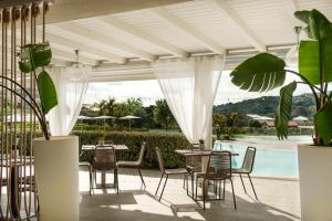 a patio with tables and chairs and a pool at The Village Chia Laguna Sardinia in Chia