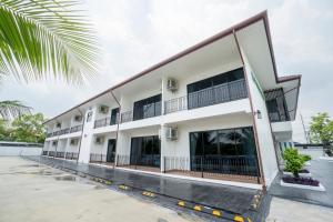 a large white building with balconies and a palm tree at PP Garden Home in Sathani Lat Krabang