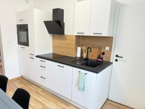 a kitchen with white cabinets and a sink at TSD Living in Kapfenberg +11 photos
