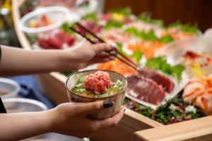 a person holding a bowl of food with chopsticks at Iwaki Washington Hotel in Iwaki