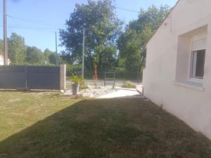 a yard next to a white building with a fence at Escapade proche de l'estuaire in Valeyrac +1 photo