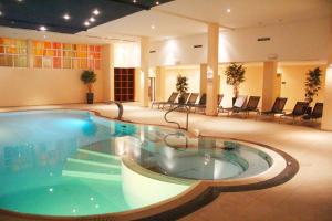 a large swimming pool in a hotel lobby with chairs at Der schöne Asten - Resort Winterberg in Winterberg