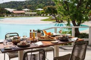 a table with food and wine and a pool at The Village Chia Laguna Sardinia in Chia