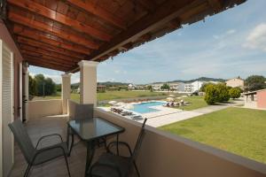 a balcony with a table and chairs and a swimming pool at Megali Luxuries Apartments in Sidari