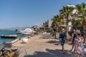 a group of people walking on a sidewalk near the water at Ocean Rythm Elounda Suite in Elounda