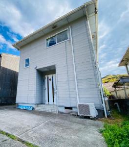 a white building with a door and a window at Guest House Rakufu in Anan