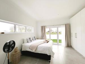 a white bedroom with a bed and a window at Villa Jabulani in Stompneusbaai
