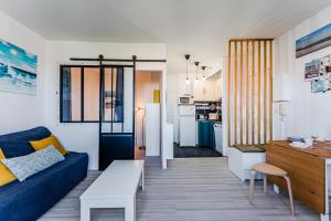 a living room with a blue couch and a kitchen at Appartement Le Mauresque in Arcachon