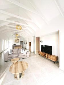 a living room with a couch and a tv and tables at Villa Jabulani in Stompneusbaai