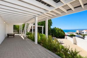 a white pergola with a bench on a patio at Kommaweer in Yzerfontein