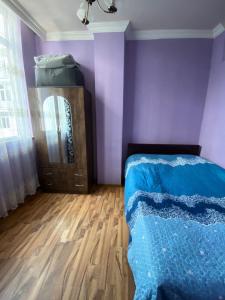 a bedroom with purple walls and a bed and a wooden floor at batumi area in Angisa