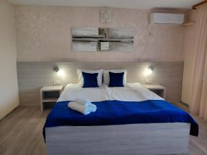 a bedroom with a large bed with blue sheets and blue pillows at Къща за гости КАТИ in Kiten