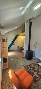 a living room with an orange chair and a stove at Studio Juncalinho - Stylish Portuguese Studio in São Teotónio