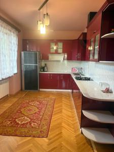 a kitchen with red cabinets and a rug on the floor at BEAUTI-House in Ijevan