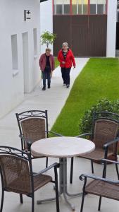 two people walking down a sidewalk with a table and chairs at Ferienhaus Trift in Illmitz