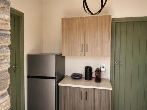 a small kitchen with a refrigerator and wooden cabinets at Bellevia Stone Pool Villa in Kouvéllai