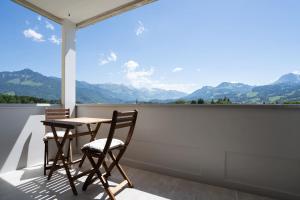 a table and chairs on a balcony with a view of mountains at La vue Appartement Gruyère in Bulle +3 photos