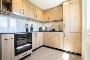 a kitchen with wooden cabinets and a black oven at La vue Appartement Gruyère in Bulle