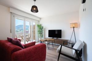 a living room with a red couch and a tv at La vue Appartement Gruyère in Bulle