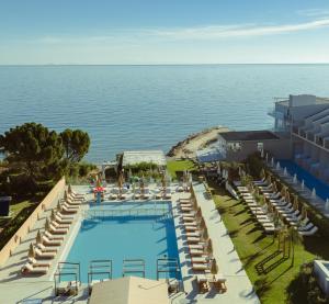 an overhead view of a swimming pool with chairs and the ocean at Amaltheia Beachfront Villas in Kypseli