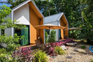 a house with an umbrella in a garden at Pool Villa Baan Suan Phrom Khiri in Nakhon Si Thammarat