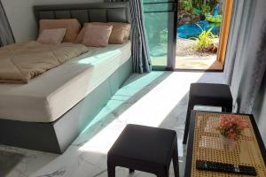 a bedroom with a bed and a table and a window at Pool Villa Baan Suan Phrom Khiri in Nakhon Si Thammarat +42 photos