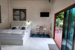 a bedroom with a bed and a desk and a television at Pool Villa Baan Suan Phrom Khiri in Nakhon Si Thammarat