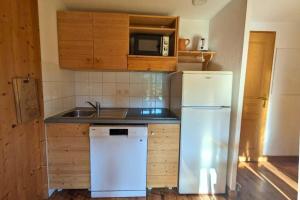 a kitchen with a white refrigerator and a sink at Chalet MÖKI accès piscine sauna in Les Déserts