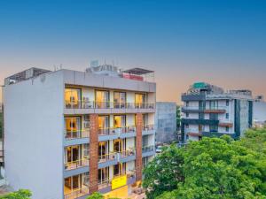 a tall white building with trees and buildings at The Hosteller Gurgaon in Gurgaon