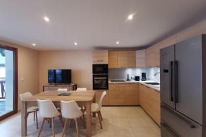 a kitchen with a wooden table and white chairs at L'écrin des neiges - Sauna in La Féclaz