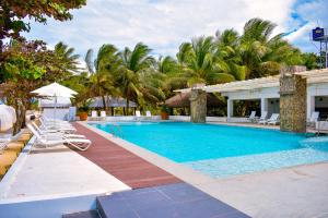 a swimming pool with chairs and palm trees at Golden Sands Destination Resorts in Daanbantayan