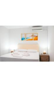 a white bedroom with a bed with two towels at Gridia Apartment in Chios