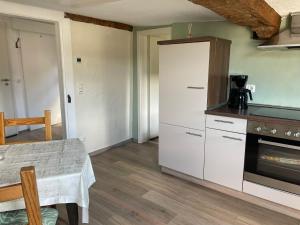 a kitchen with white cabinets and a table and a stove at Ferienhaus an der Felsenkirche in Idar-Oberstein