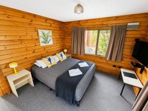 a bedroom with a bed and a flat screen tv at Forest Peak Motel in Hanmer Springs