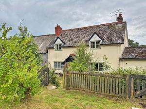 an old white house with a wooden fence at Finest Retreats - Coachmans Cottage in Lapford