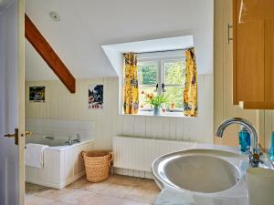 a bathroom with a tub and a sink and a window at Finest Retreats - Coachmans Cottage in Lapford +9 photos