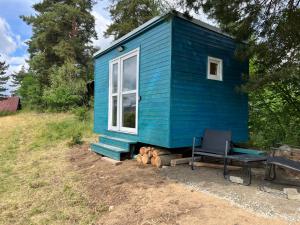a blue tiny house with a bench and a chair at Samoobslužná maringotka in Žihobce
