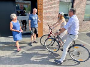 a man riding a bike on a sidewalk with a woman at Gîte La Siroperie in Wanze