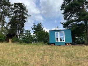 a blue tiny house sitting in a field at Samoobslužná maringotka in Žihobce
