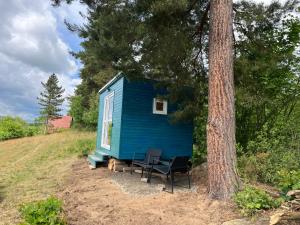 a blue tiny house sitting next to a tree at Samoobslužná maringotka in Žihobce