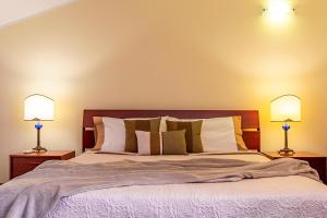 a bedroom with a large bed with two lamps at Villa Corte Fiorita in Aci SantʼAntonio +22 photos