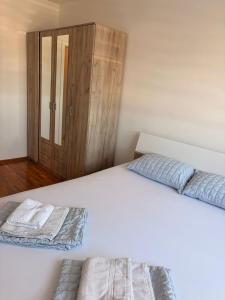 a white bed with two pillows and a wooden cabinet at Apartman Enigma II in Ruma